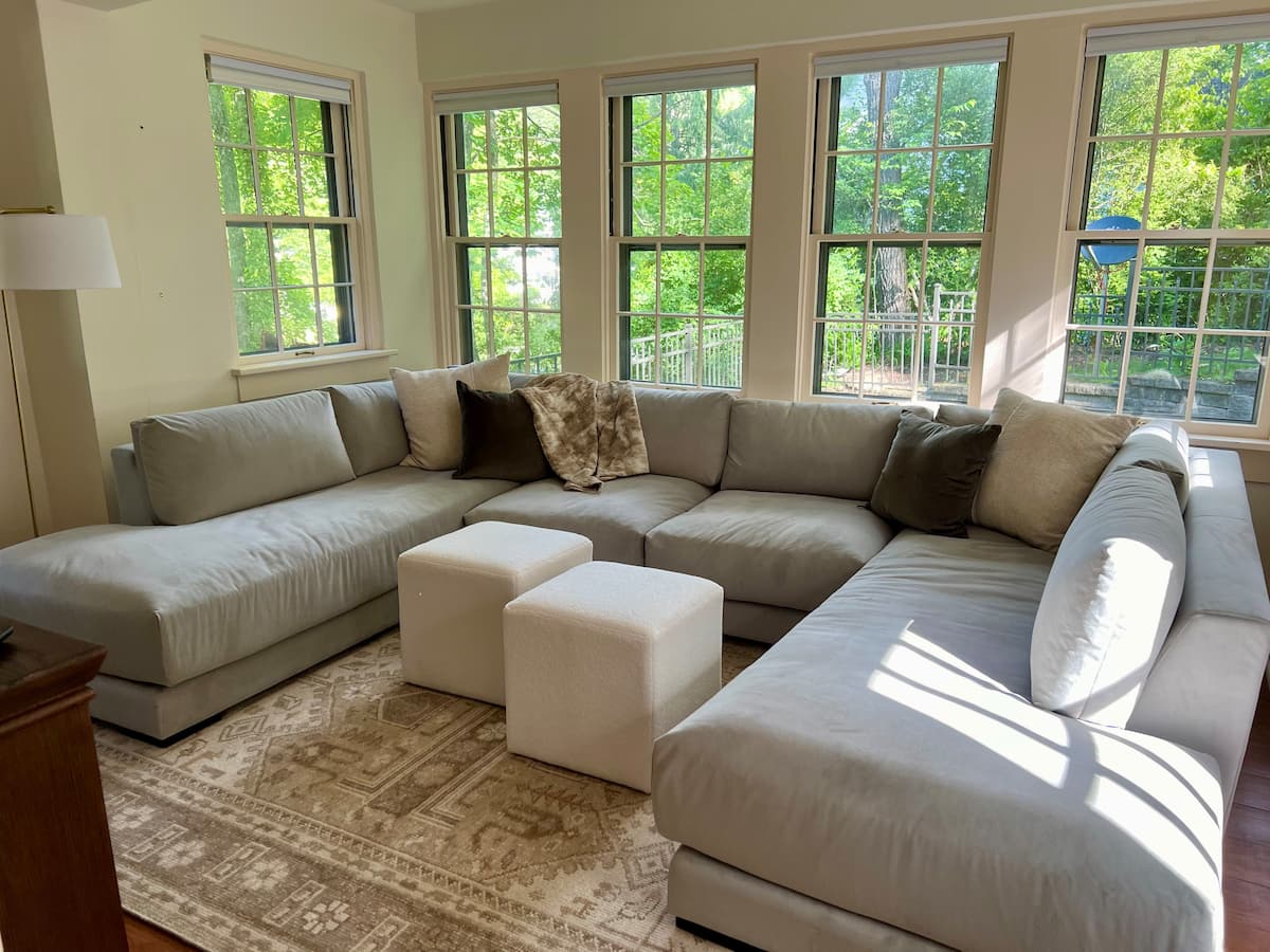 The bright sunroom with a large sectional and windows overlooking the garden