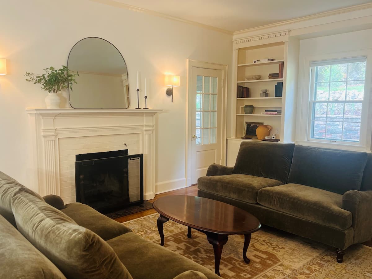 The living room with original fireplace, comfortable sofas, and built-in bookshelves