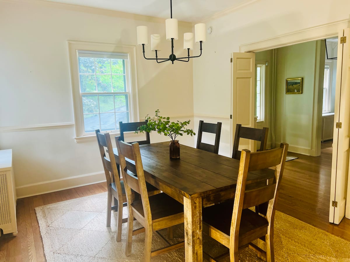 The dining room with a wooden table, six chairs, and a view toward the kitchen